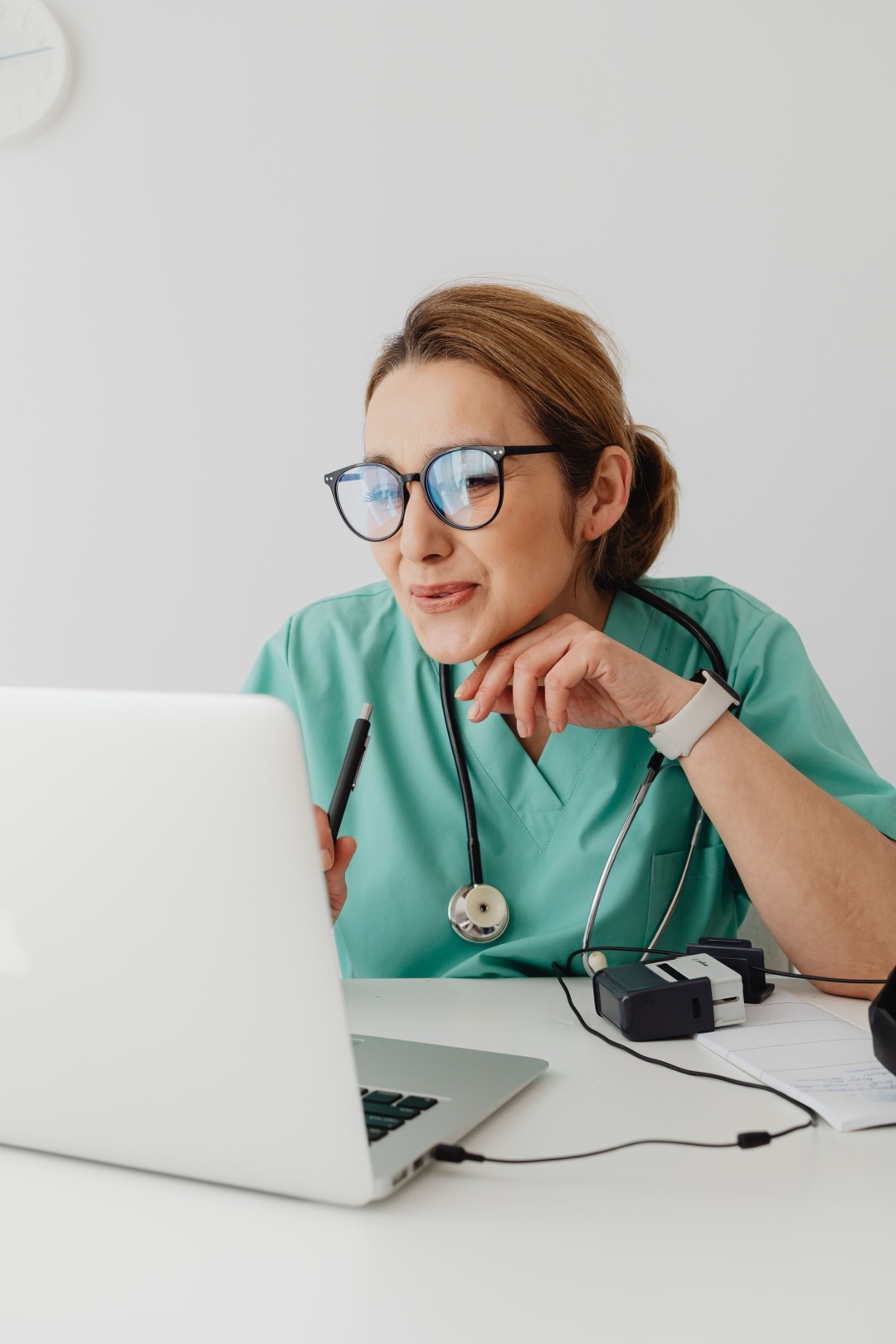 Médica sorrindo em videochamada no notebook do consultório